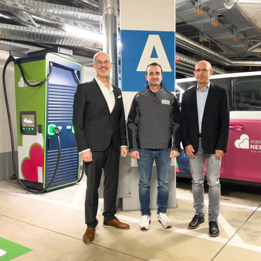 Dominique Kinzkofer (SWN), Christian Simon (Max Bögl) und Christoph Maier (Max Bögl) nehmen Schnellladesäule (DC) in der Parkgarage im Neuen Markt in Betrieb